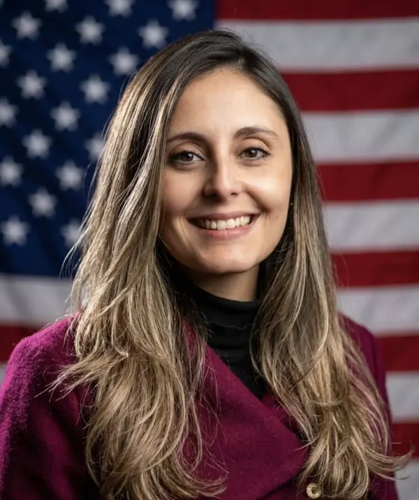Thais Fabrini sorrindo em frente à bandeira americana